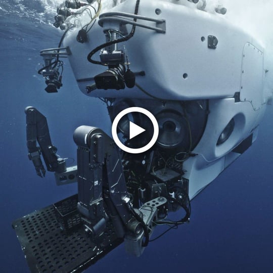 Human-occupied submersible Alvin floats at the sea surface, white waters sloshing above it.