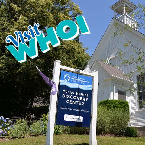 A picture of a sign outside of a tall steeple-like building that reads "Woods Hole Oceanographic Institution Ocean Science Discovery Center.