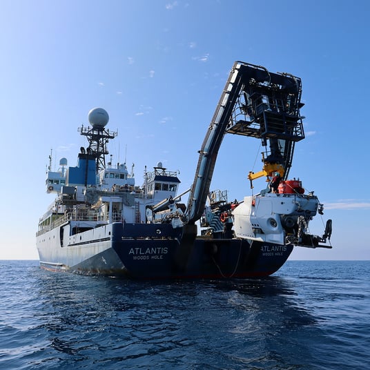 R/V Neil Armstrong extends an A-frame with HOV Alvin over the aft deck and above the water.