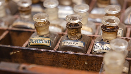 A close-up of three rows of old medicine vials separated by wooden partitions 